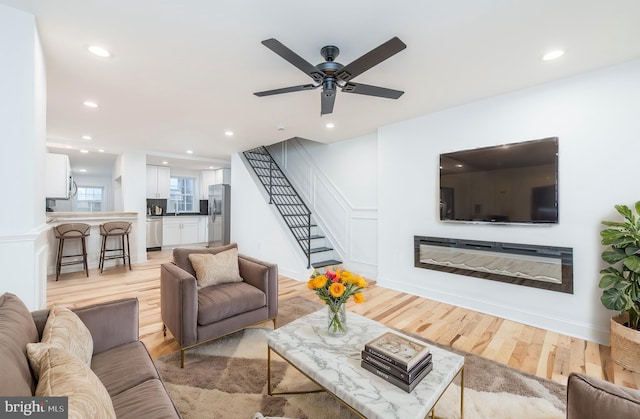 living room with light hardwood / wood-style floors and ceiling fan