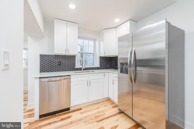 kitchen with sink, white cabinetry, stainless steel appliances, and light wood-type flooring