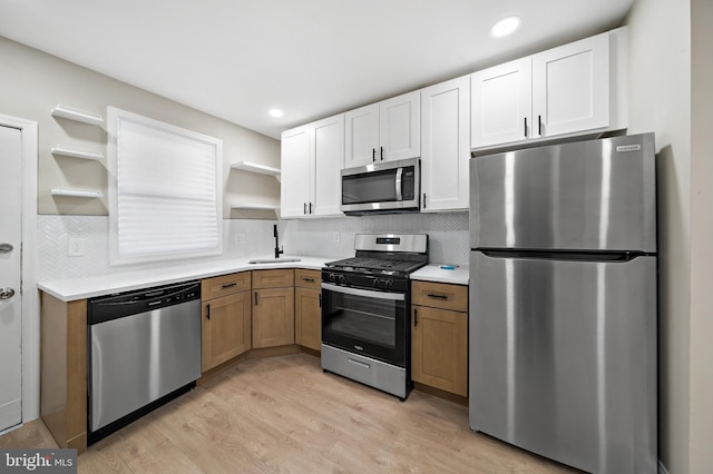 kitchen featuring white cabinetry, sink, tasteful backsplash, appliances with stainless steel finishes, and light wood-type flooring