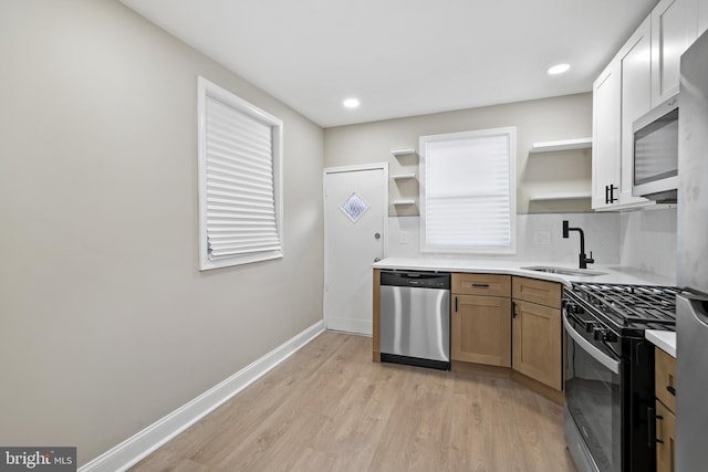 kitchen with appliances with stainless steel finishes, light hardwood / wood-style floors, and sink