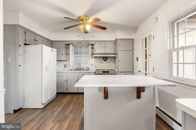 kitchen with a kitchen bar, dark hardwood / wood-style flooring, gray cabinetry, sink, and white refrigerator with ice dispenser