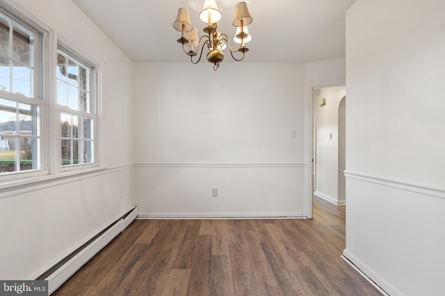 spare room featuring dark hardwood / wood-style floors, a baseboard heating unit, and a notable chandelier