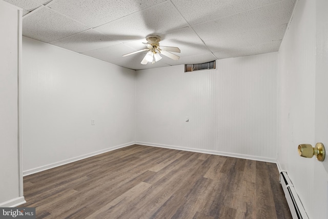 unfurnished room featuring dark hardwood / wood-style flooring, a baseboard radiator, and a drop ceiling