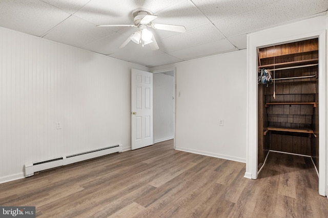 interior space with a paneled ceiling, hardwood / wood-style flooring, ceiling fan, and a baseboard heating unit