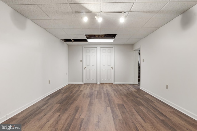 interior space with a paneled ceiling, rail lighting, and dark hardwood / wood-style floors