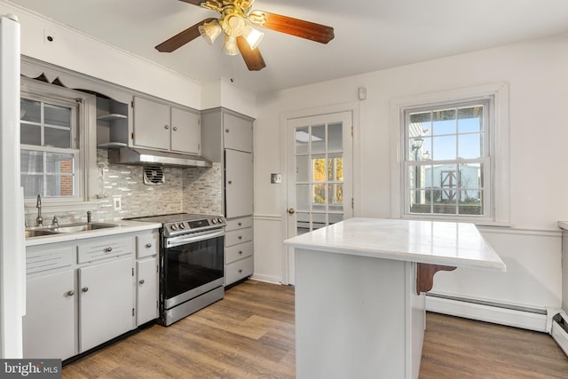 kitchen with a healthy amount of sunlight, sink, stainless steel range with electric cooktop, and hardwood / wood-style floors