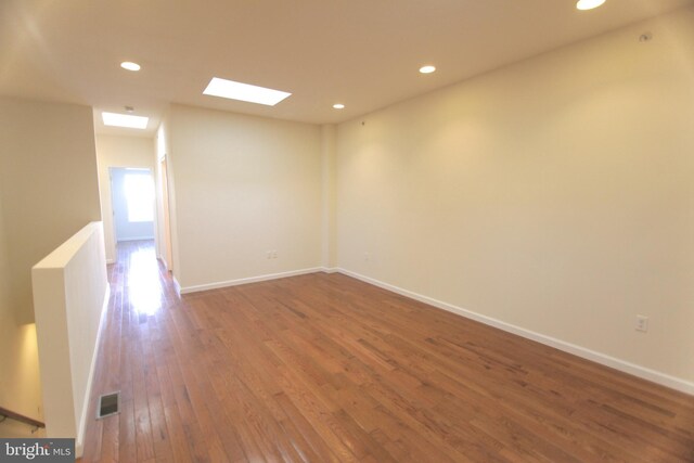 spare room featuring wood-type flooring and a skylight