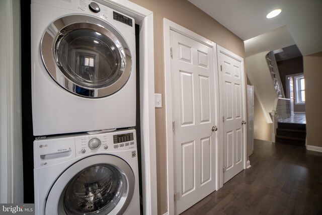 clothes washing area featuring dark wood-type flooring and stacked washing maching and dryer