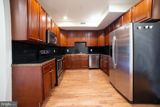 kitchen featuring decorative backsplash, sink, light wood-type flooring, and stainless steel appliances