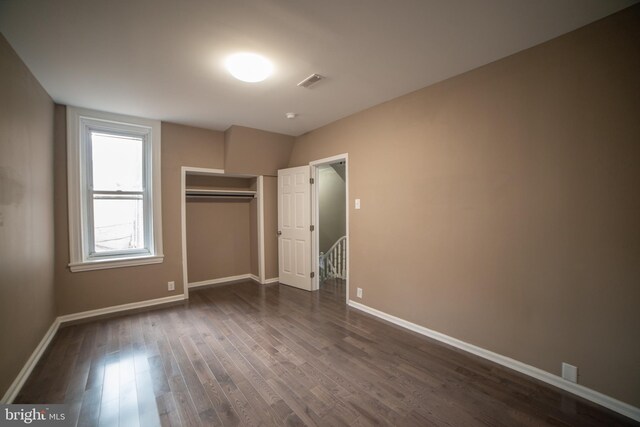 unfurnished bedroom with a closet and dark hardwood / wood-style flooring