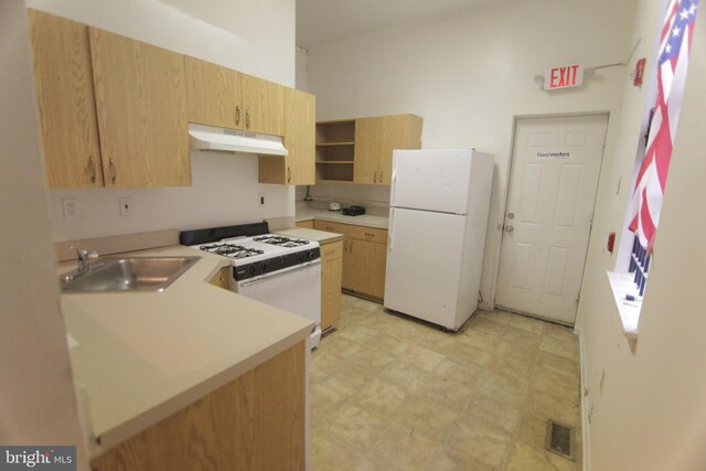 kitchen with kitchen peninsula, light brown cabinetry, white appliances, and sink