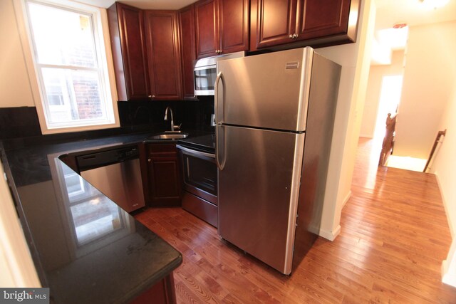 kitchen featuring appliances with stainless steel finishes, backsplash, light hardwood / wood-style flooring, and sink