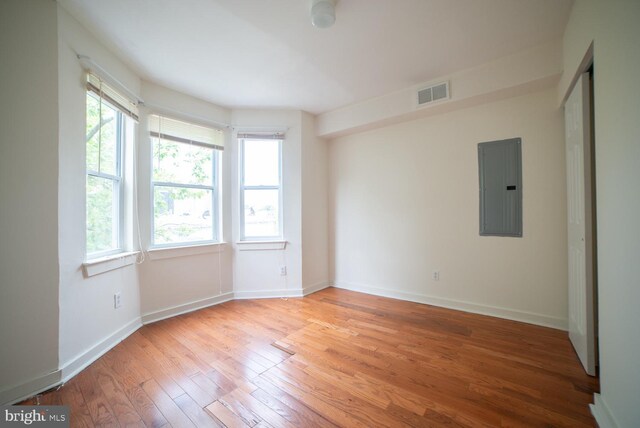 unfurnished room with electric panel and light hardwood / wood-style flooring