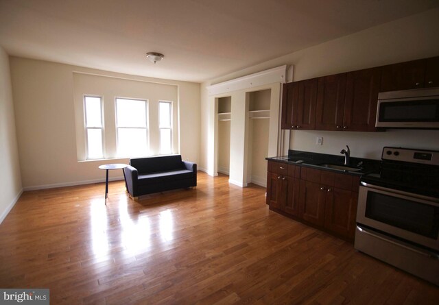 kitchen with sink, light wood-type flooring, stainless steel appliances, and dark brown cabinetry