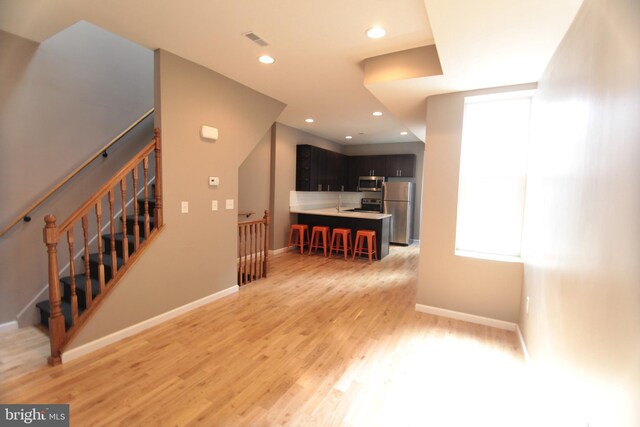 interior space featuring a kitchen bar, appliances with stainless steel finishes, light wood-type flooring, and a kitchen island