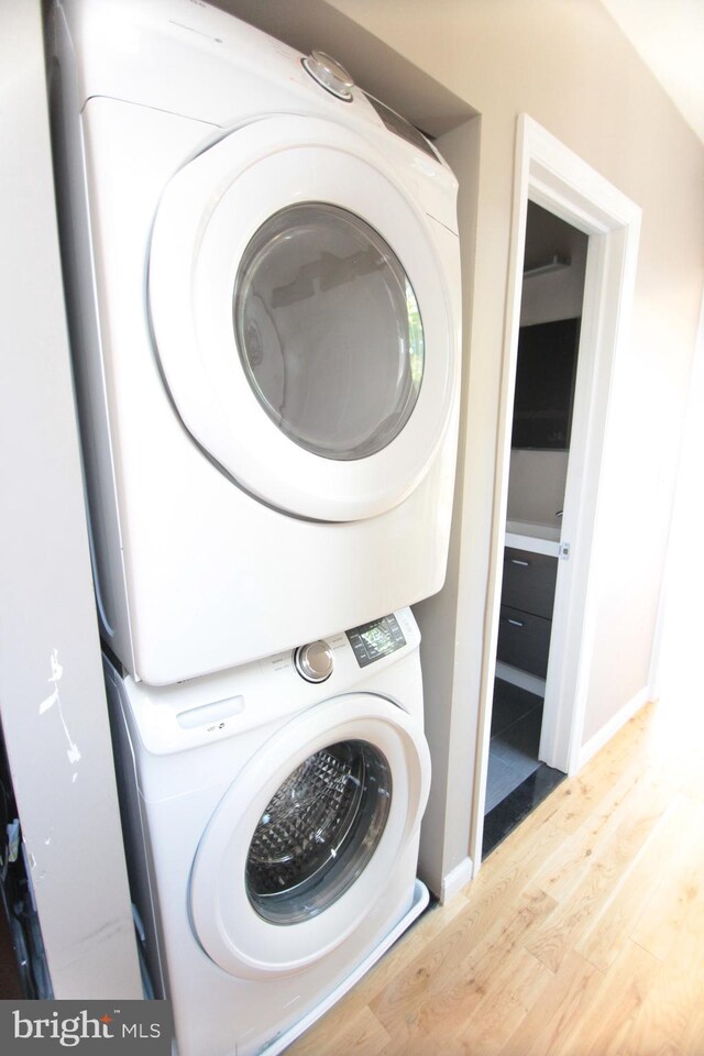 washroom with wood-type flooring and stacked washer and dryer