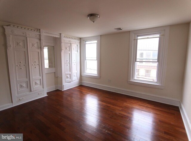 unfurnished bedroom featuring dark hardwood / wood-style flooring and multiple windows