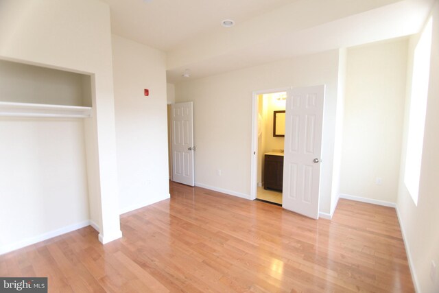 unfurnished bedroom with connected bathroom, light hardwood / wood-style flooring, and a closet