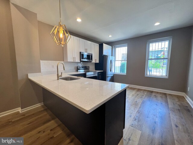 kitchen with sink, hanging light fixtures, stainless steel appliances, kitchen peninsula, and light wood-type flooring