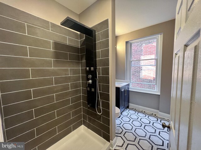 bathroom with vanity, toilet, and tiled shower