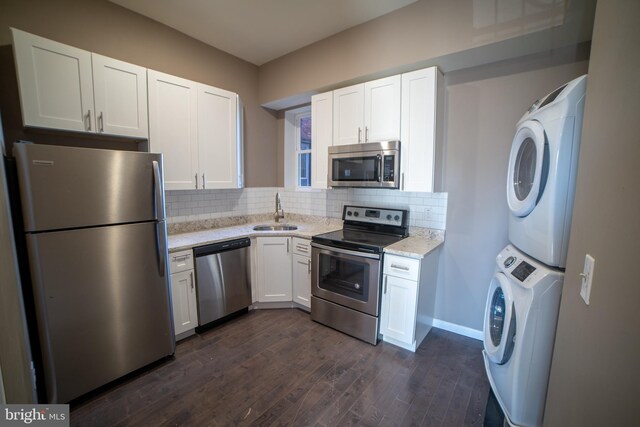 kitchen featuring sink, dark wood-type flooring, stainless steel appliances, white cabinets, and stacked washer and clothes dryer