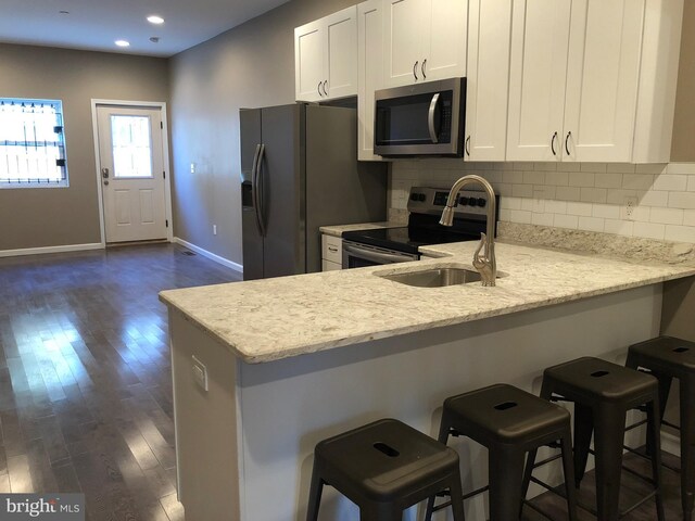 kitchen featuring light stone countertops, appliances with stainless steel finishes, and a breakfast bar area