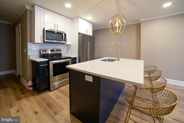 kitchen with decorative light fixtures, white cabinetry, sink, and appliances with stainless steel finishes