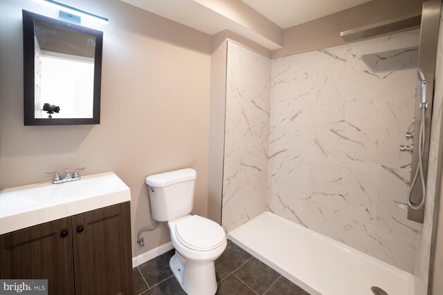 bathroom with tiled shower, tile patterned floors, vanity, and toilet