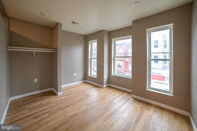 unfurnished bedroom with a closet, light wood-type flooring, and multiple windows