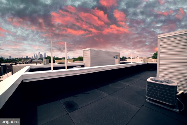 patio terrace at dusk featuring central air condition unit and a balcony