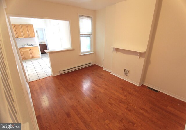 empty room with a baseboard radiator, light hardwood / wood-style flooring, and sink