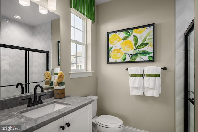 bathroom featuring vanity, toilet, and a shower with shower door