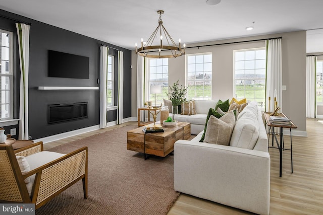 living room with light hardwood / wood-style flooring, plenty of natural light, and a notable chandelier