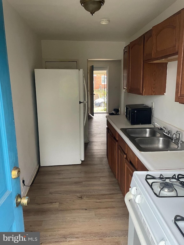 kitchen featuring sink, white appliances, and light wood-type flooring