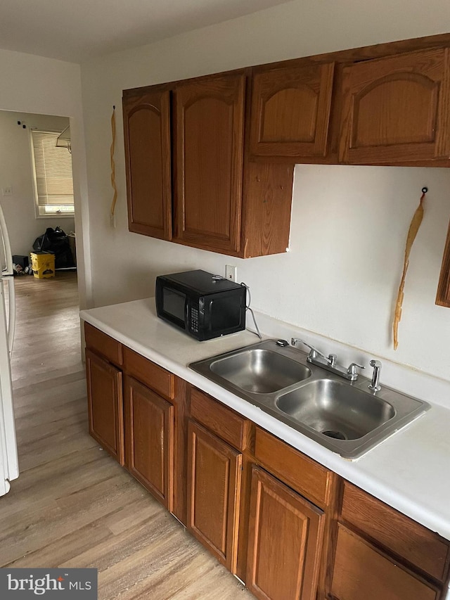 kitchen with sink, light hardwood / wood-style flooring, and white refrigerator