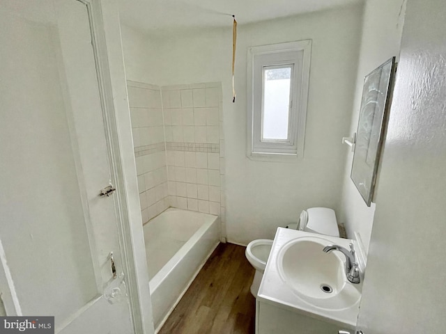 full bathroom featuring wood-type flooring, toilet, tiled shower / bath combo, and vanity