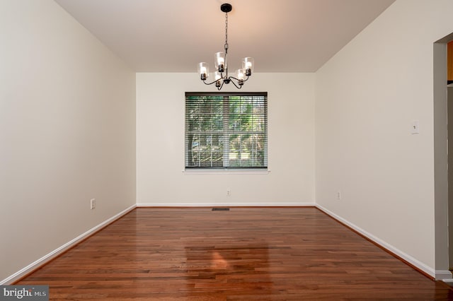 unfurnished dining area featuring dark wood-type flooring and an inviting chandelier