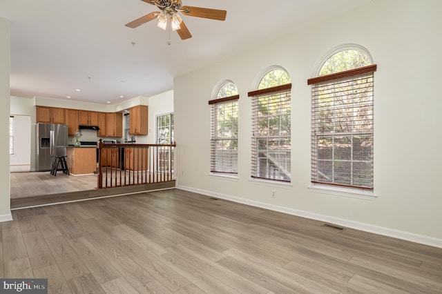 unfurnished living room with ceiling fan and light hardwood / wood-style flooring