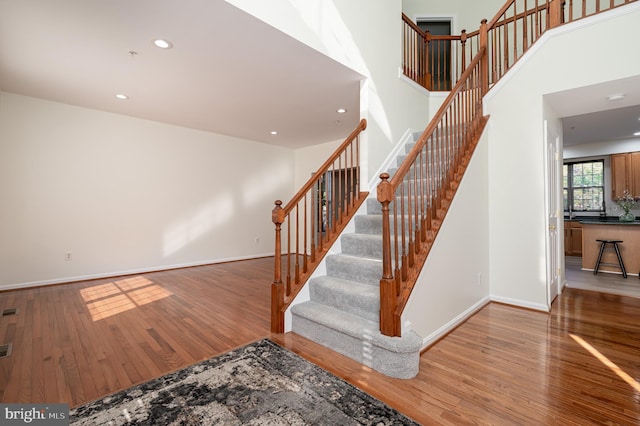 stairway featuring hardwood / wood-style floors and a towering ceiling