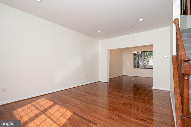 spare room with a chandelier and dark hardwood / wood-style flooring