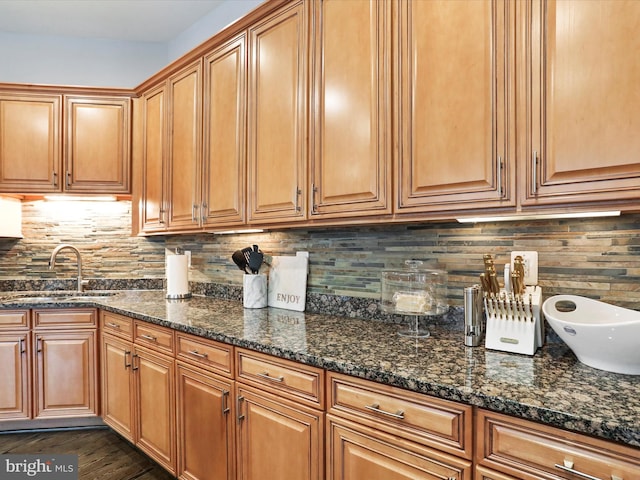 kitchen featuring backsplash, dark stone countertops, and sink