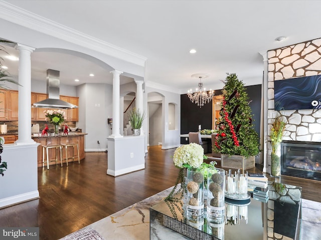 dining space with a chandelier, ornamental molding, a fireplace, and dark wood-type flooring