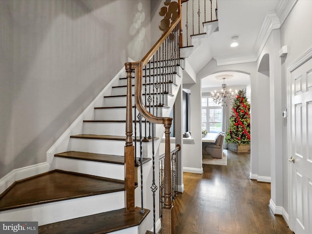 stairway featuring crown molding, wood-type flooring, and a notable chandelier