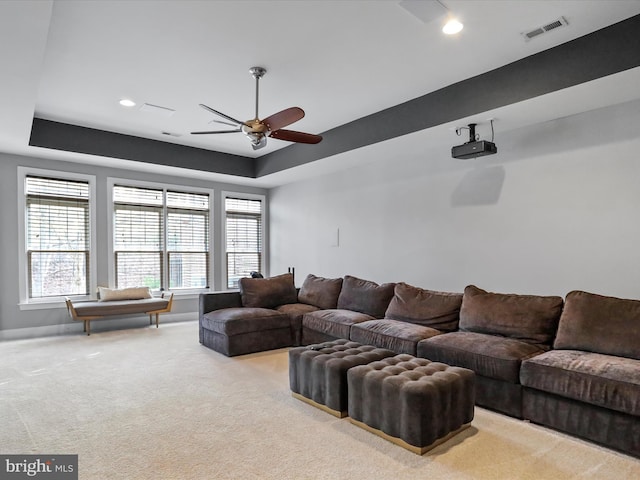 carpeted living room featuring a raised ceiling and ceiling fan