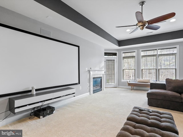 carpeted cinema room with ceiling fan and a premium fireplace