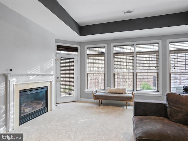 carpeted living room featuring a high end fireplace and a wealth of natural light