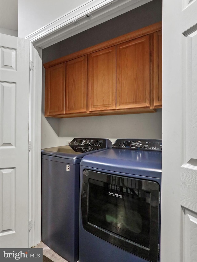 laundry area featuring washing machine and clothes dryer and cabinets