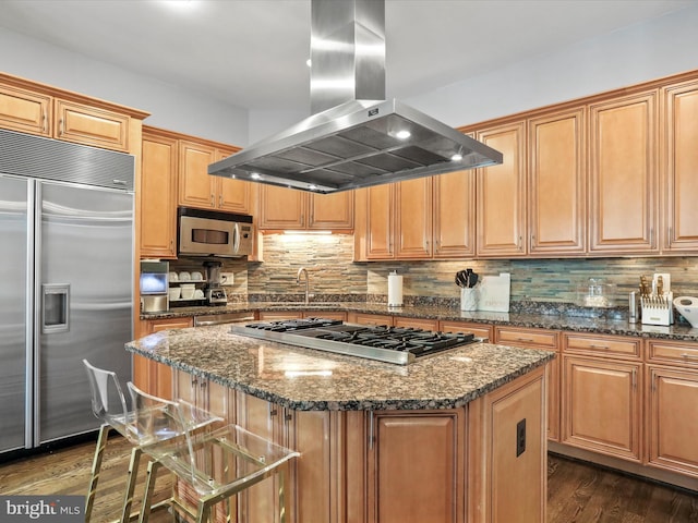 kitchen featuring dark stone counters, island exhaust hood, a kitchen island, and stainless steel appliances