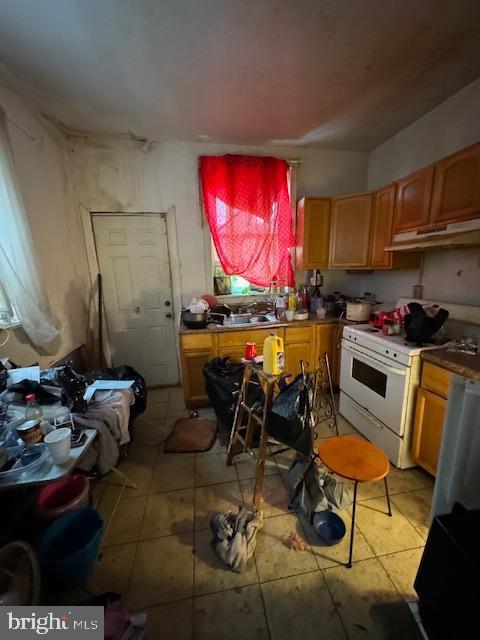 kitchen with sink, light tile patterned floors, and white range