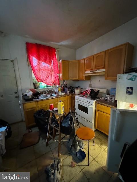 kitchen featuring light tile patterned floors, white range, fridge, and sink